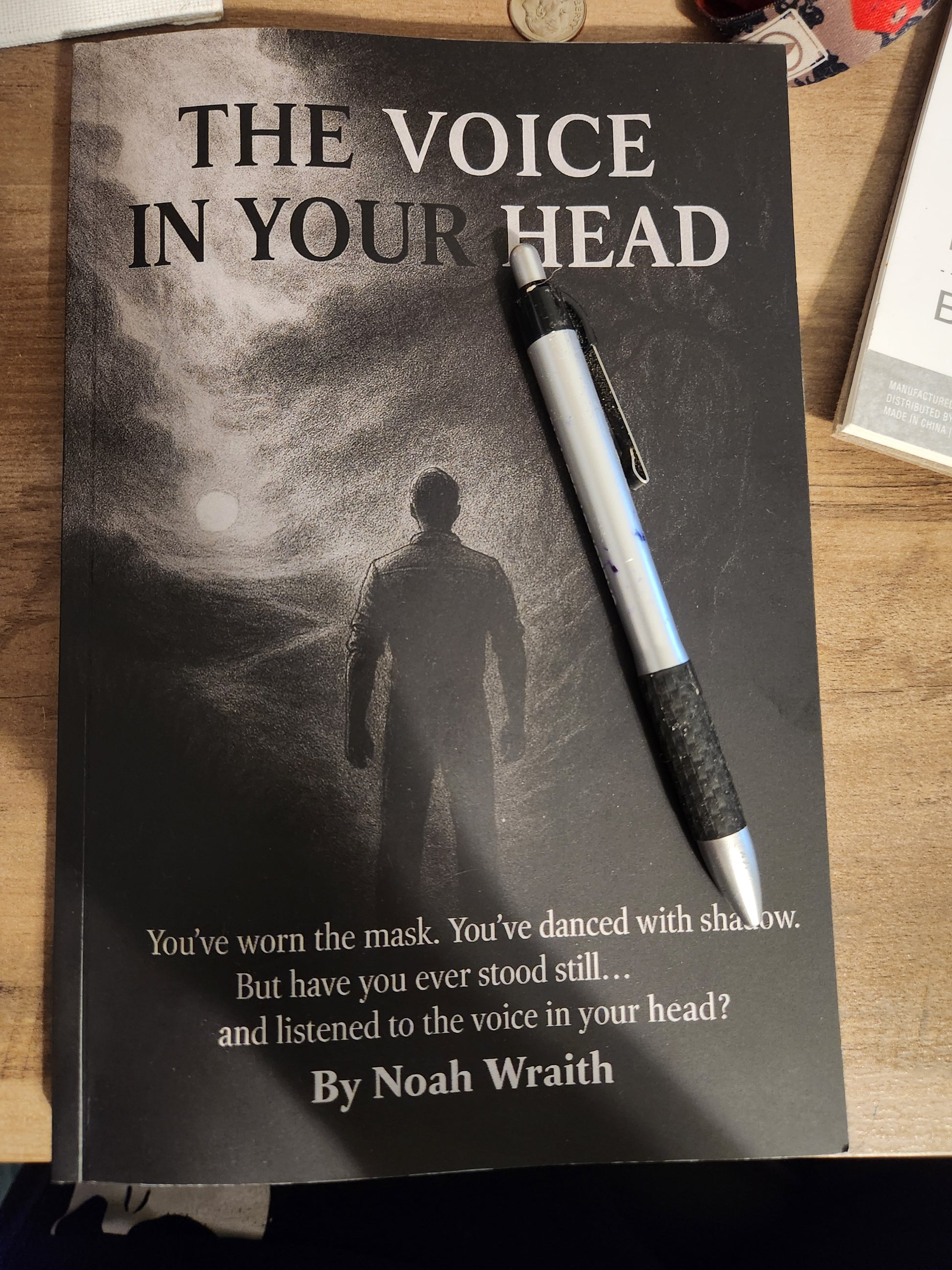 Book titled 'The Voice in Your Head' with a pen on a wooden surface